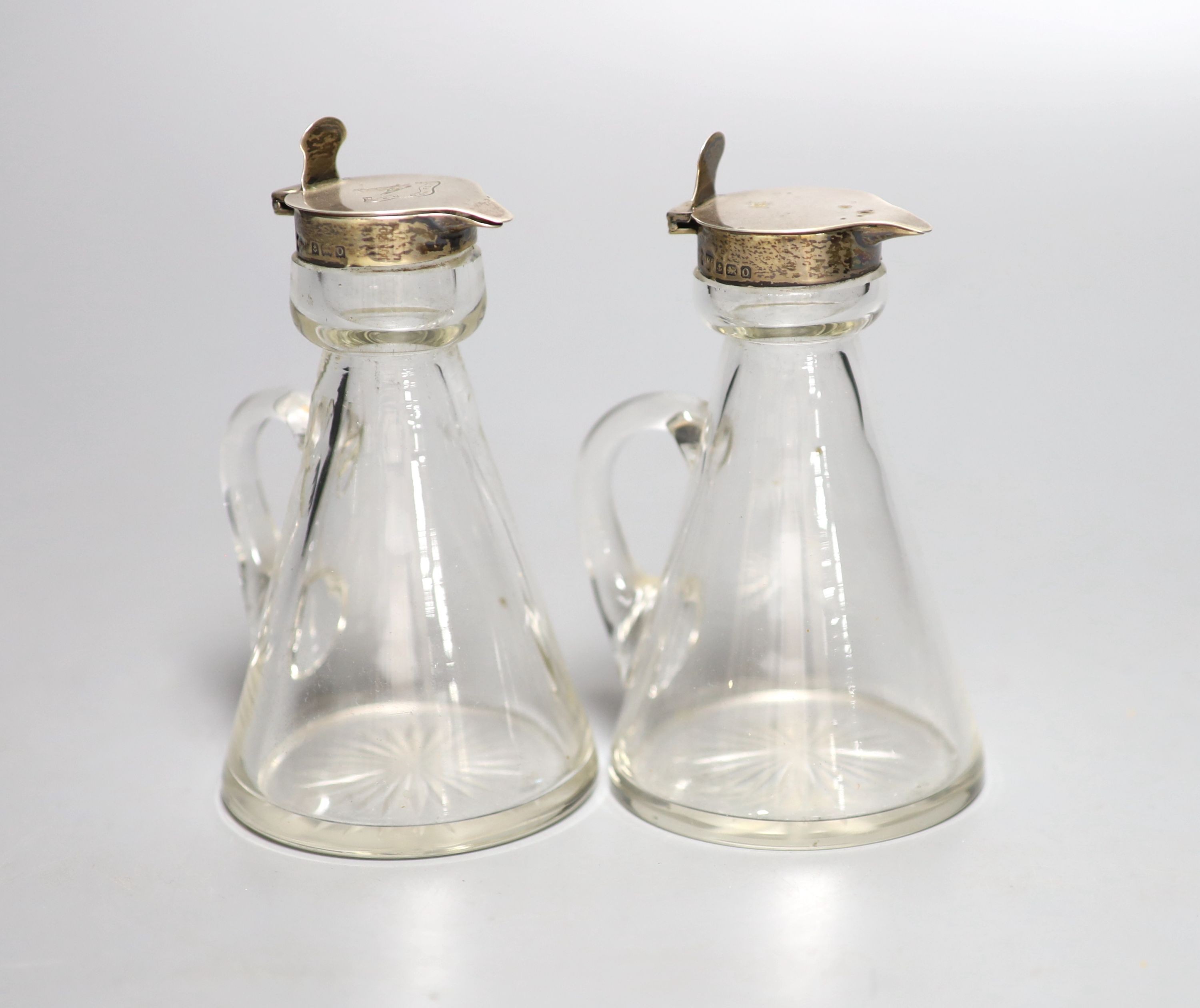 A near pair of George V silver mounted glass whisky tots (one a.f.), Mappin & Webb, Birmingham, 1913, one with engraved crest to cover, 12.1cm.